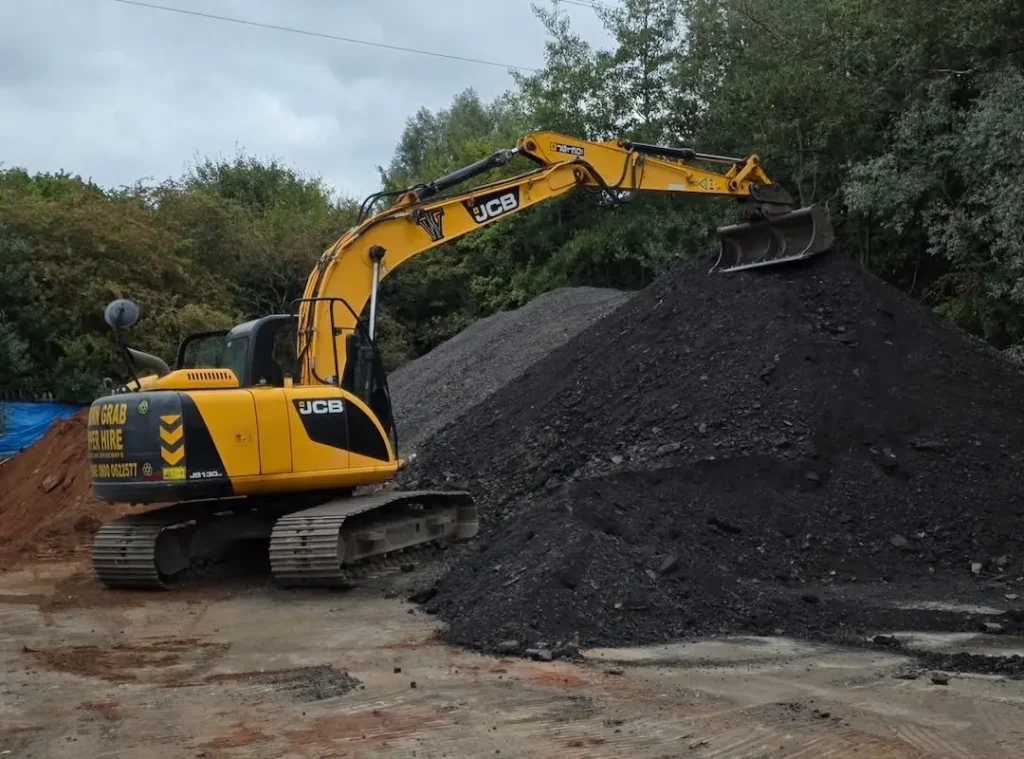 a yellow excavator with a bucket on top of a pile of dirt